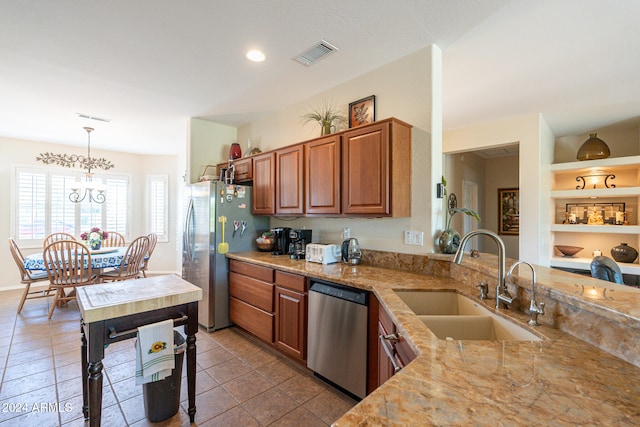 kitchen featuring stainless steel appliances, light stone countertops, pendant lighting, and sink