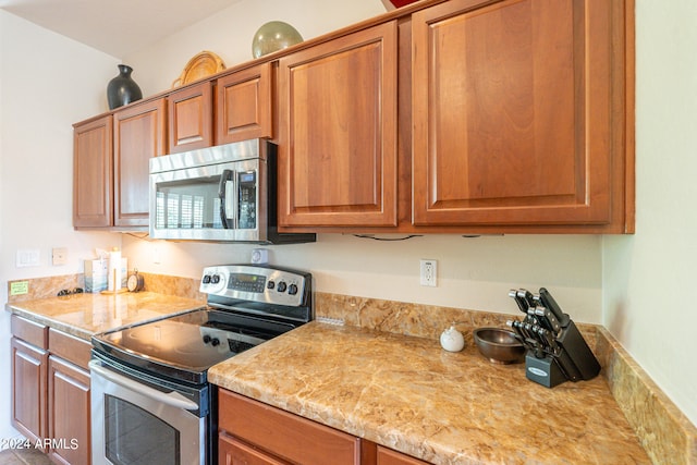 kitchen with light stone countertops and appliances with stainless steel finishes