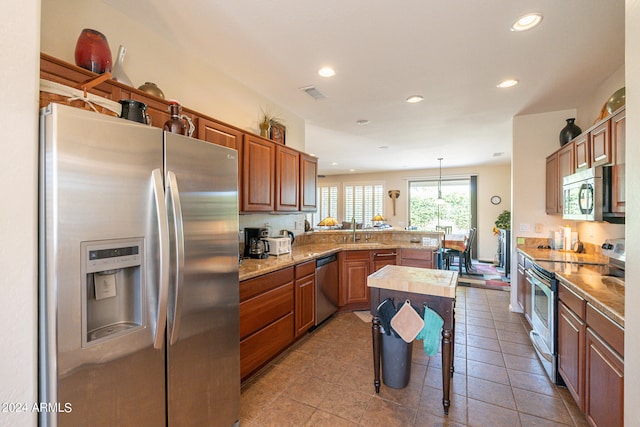 kitchen with a center island, sink, pendant lighting, kitchen peninsula, and appliances with stainless steel finishes