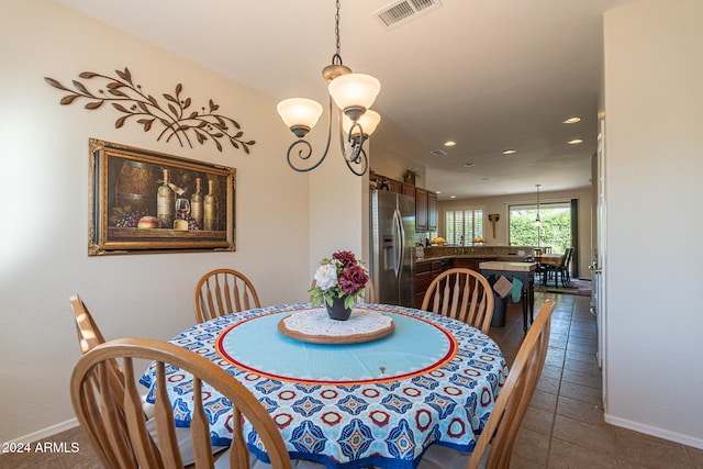 dining area featuring dark tile patterned floors and an inviting chandelier