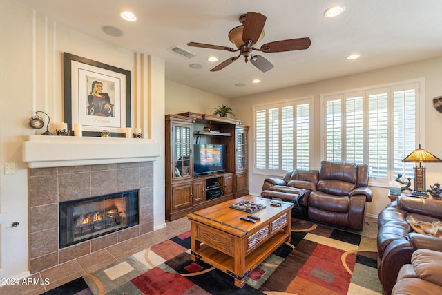 living room featuring tile patterned flooring, ceiling fan, and a tiled fireplace