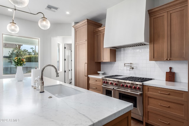 kitchen featuring pendant lighting, custom exhaust hood, double oven range, backsplash, and sink