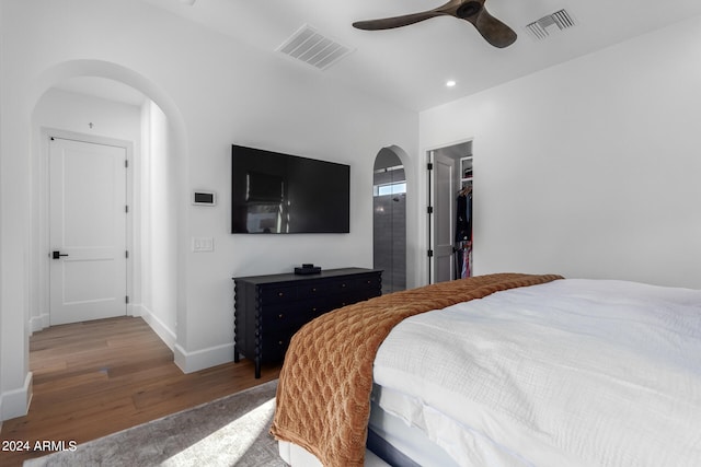 bedroom with ceiling fan, a closet, wood-type flooring, and a spacious closet