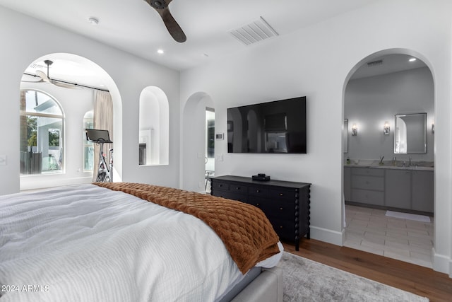 bedroom with hardwood / wood-style flooring, ceiling fan, sink, and connected bathroom