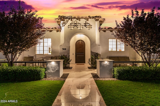 exterior entry at dusk featuring a lawn