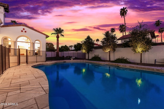 pool at dusk featuring a patio area