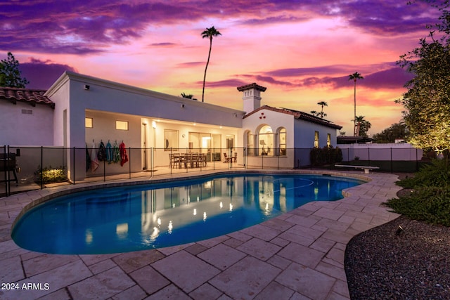 pool at dusk with a patio area