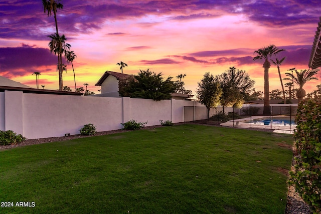 yard at dusk featuring a fenced in pool