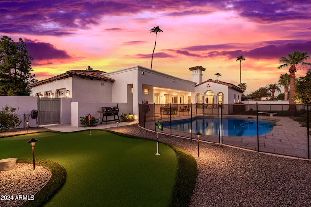 pool at dusk featuring a patio