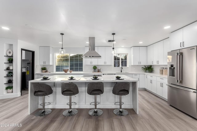 kitchen with white cabinets, high end refrigerator, a kitchen island, and exhaust hood