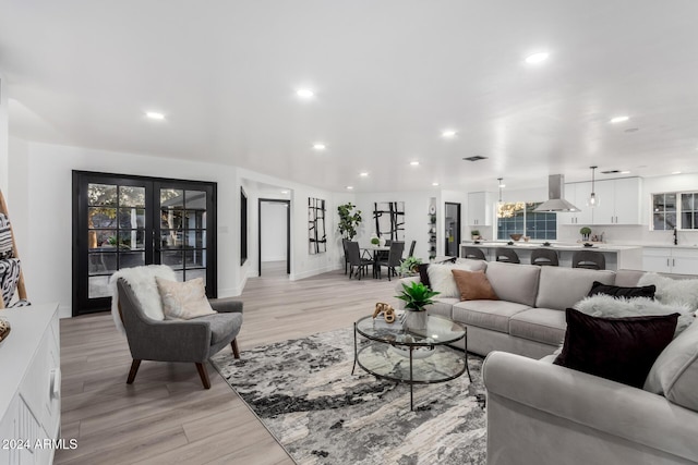 living room with french doors, light hardwood / wood-style floors, and sink