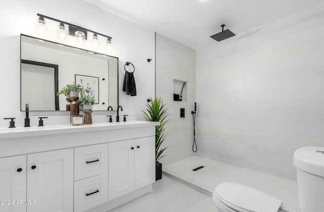 bathroom featuring a tile shower, vanity, and toilet