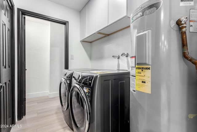 washroom featuring electric water heater, light hardwood / wood-style flooring, cabinets, and independent washer and dryer