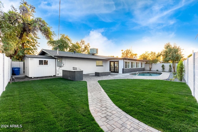 rear view of house featuring a lawn, a patio area, a fenced in pool, and central AC