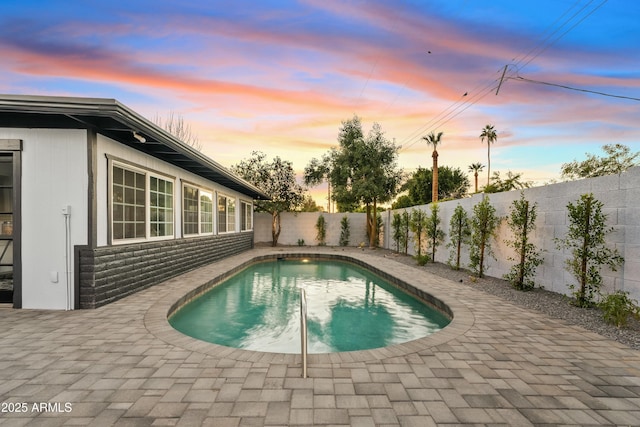 pool at dusk featuring a patio area