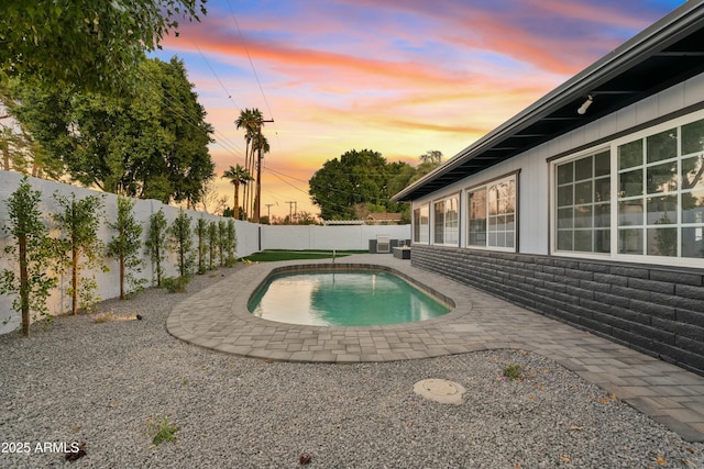 pool at dusk with a patio and cooling unit