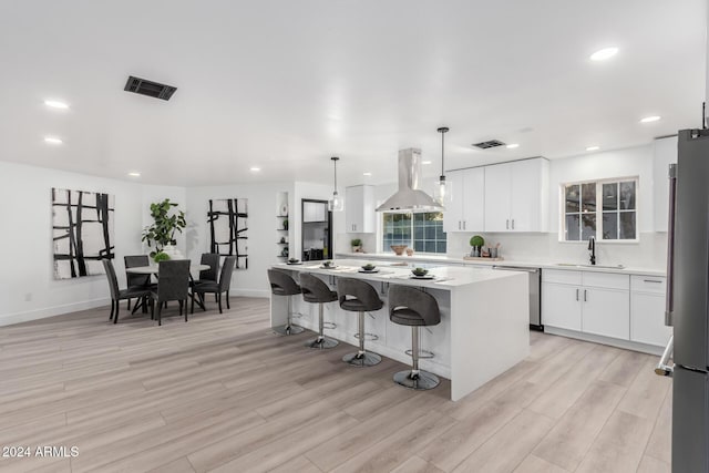 kitchen with white cabinets, a center island, island exhaust hood, and appliances with stainless steel finishes