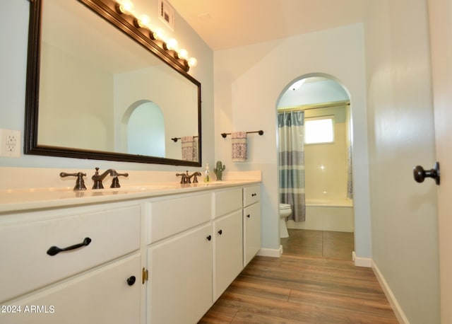 full bathroom featuring vanity, hardwood / wood-style flooring, toilet, and shower / bathtub combination with curtain