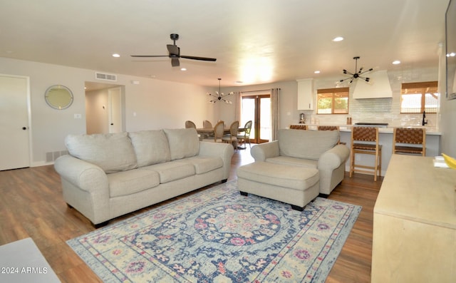 living room with light hardwood / wood-style floors and ceiling fan with notable chandelier