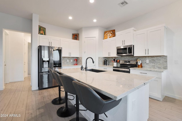 kitchen featuring white cabinets, appliances with stainless steel finishes, a kitchen island with sink, and sink