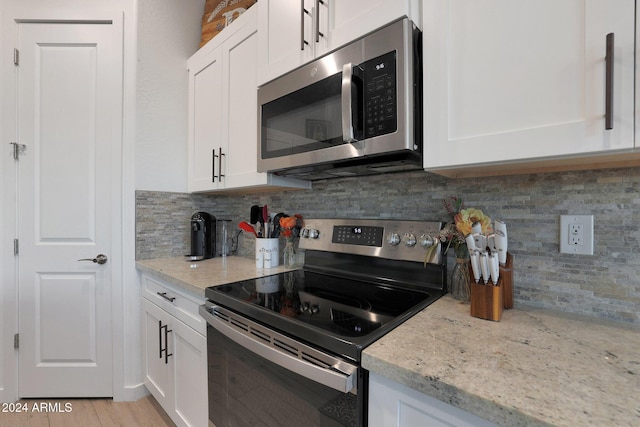 kitchen with light stone counters, stainless steel appliances, white cabinets, and tasteful backsplash