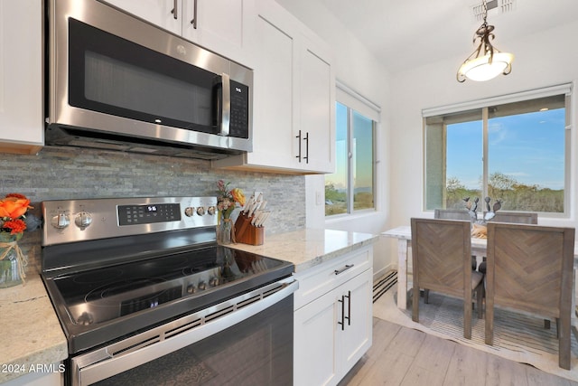 kitchen with white cabinetry, light hardwood / wood-style floors, decorative backsplash, light stone countertops, and appliances with stainless steel finishes