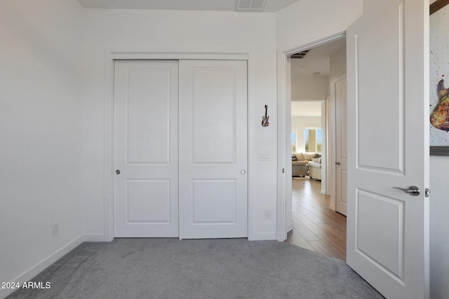 unfurnished bedroom featuring light colored carpet and a closet