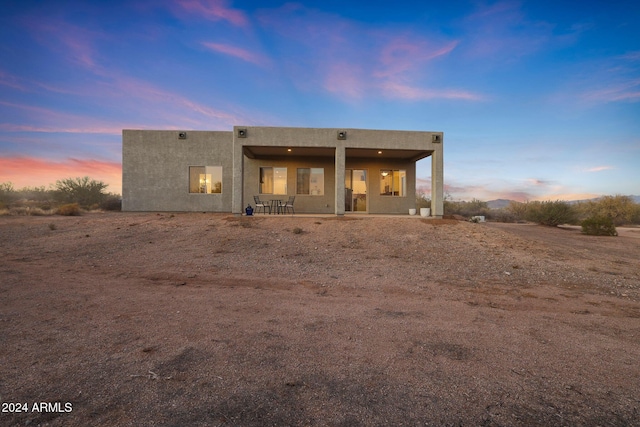 back house at dusk featuring a patio area