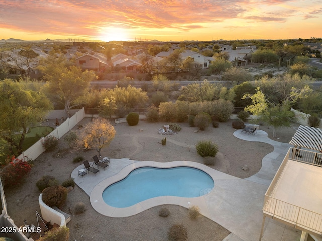 pool at dusk featuring a fenced backyard, an outdoor pool, and a patio