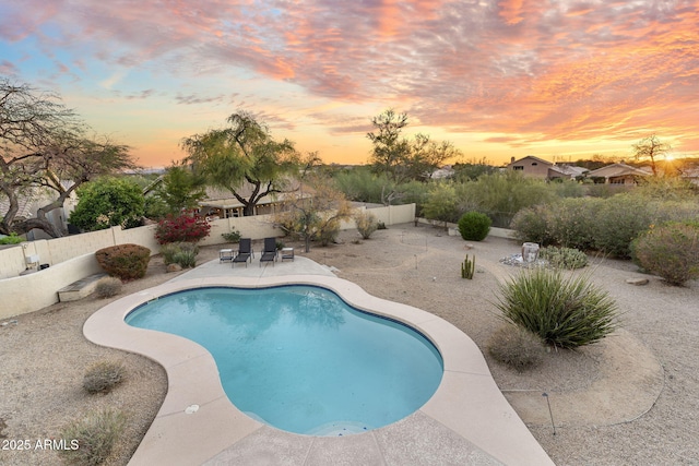 pool at dusk with a fenced in pool, a fenced backyard, and a patio area