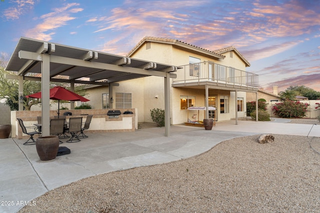 rear view of house with stucco siding, area for grilling, a balcony, a pergola, and a patio