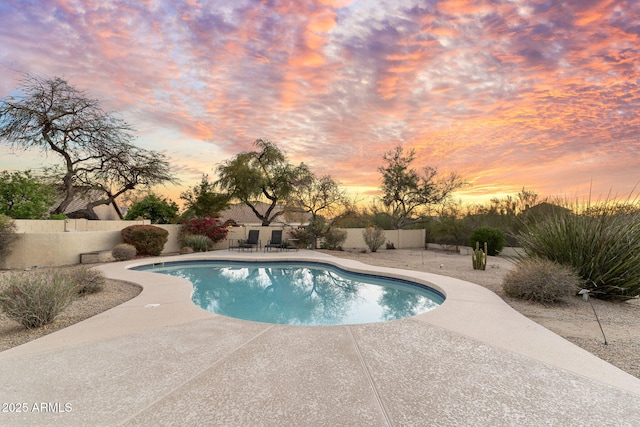 pool at dusk featuring a fenced backyard, a fenced in pool, and a patio