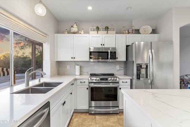 kitchen with a sink, white cabinetry, tasteful backsplash, and appliances with stainless steel finishes