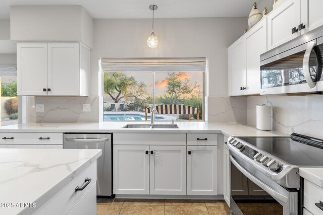 kitchen with white cabinets, decorative backsplash, a sink, and stainless steel appliances