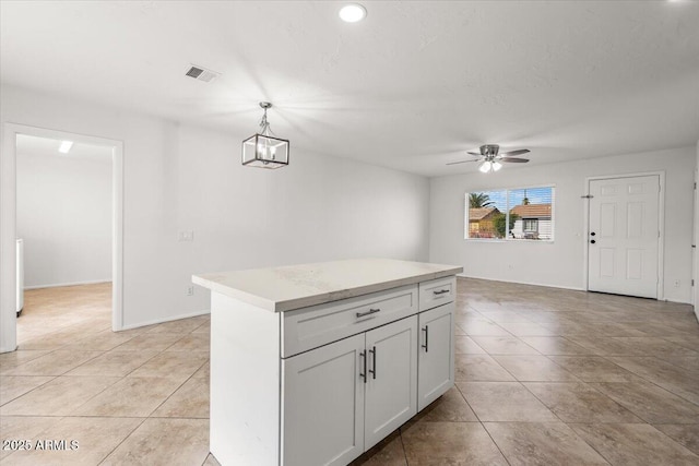 kitchen featuring light tile patterned floors, ceiling fan with notable chandelier, light countertops, a center island, and decorative light fixtures