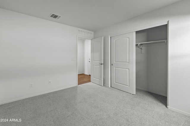 unfurnished bedroom with light carpet and a closet