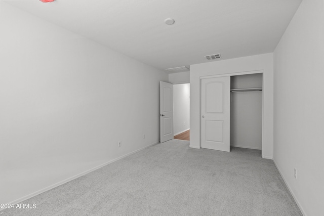 unfurnished bedroom featuring light colored carpet and a closet