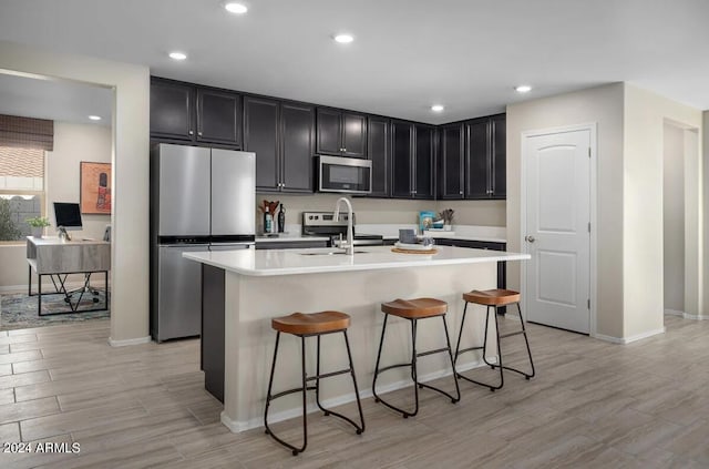 kitchen featuring a breakfast bar area, an island with sink, and stainless steel appliances