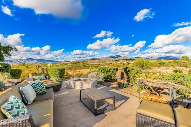 view of patio with a mountain view and an outdoor living space with a fire pit