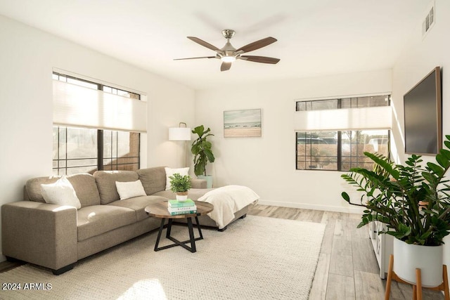 living room with light wood-type flooring, ceiling fan, and a healthy amount of sunlight