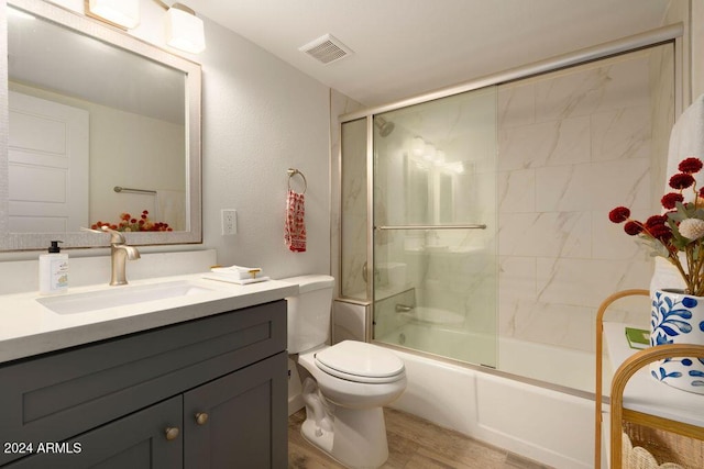 full bathroom featuring hardwood / wood-style flooring, combined bath / shower with glass door, toilet, and vanity