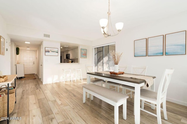 dining area with an inviting chandelier and light hardwood / wood-style flooring