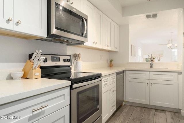 kitchen featuring white cabinets, sink, light wood-type flooring, and stainless steel appliances