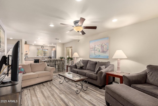 living room with sink, ceiling fan, and light hardwood / wood-style flooring