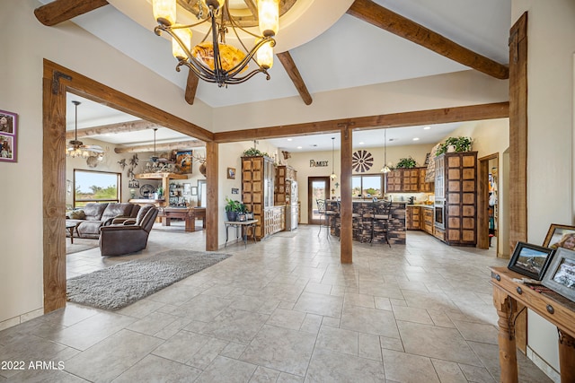 interior space featuring beamed ceiling, a towering ceiling, and ceiling fan with notable chandelier