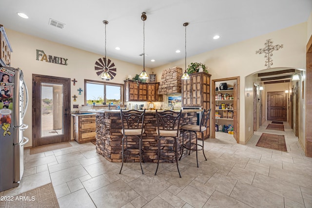 kitchen featuring pendant lighting, stainless steel refrigerator, and a breakfast bar area