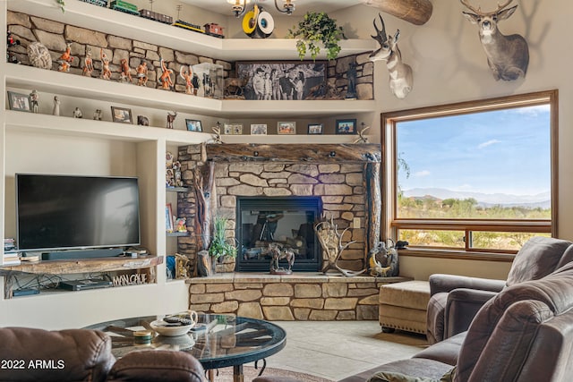 tiled living room featuring a mountain view, a stone fireplace, and a healthy amount of sunlight