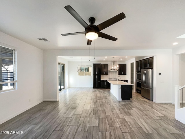 kitchen with decorative backsplash, stainless steel appliances, a kitchen island with sink, and a healthy amount of sunlight