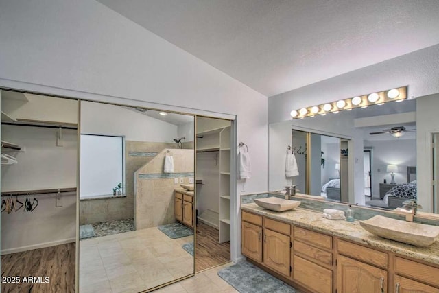 bathroom featuring vaulted ceiling, a shower, vanity, and ceiling fan