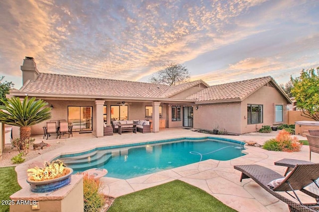 pool at dusk with a patio area and outdoor lounge area